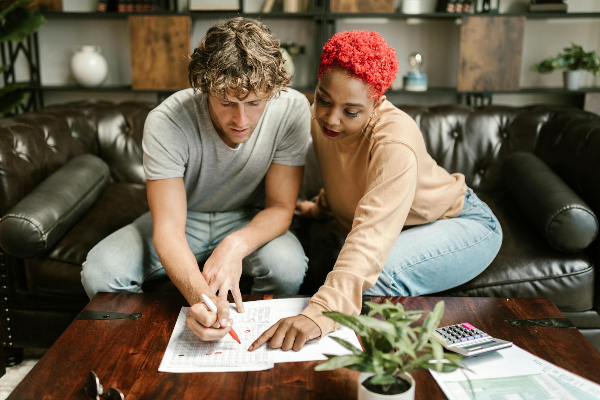 A man and woman collaborating on a project at home, focusing on paperwork.