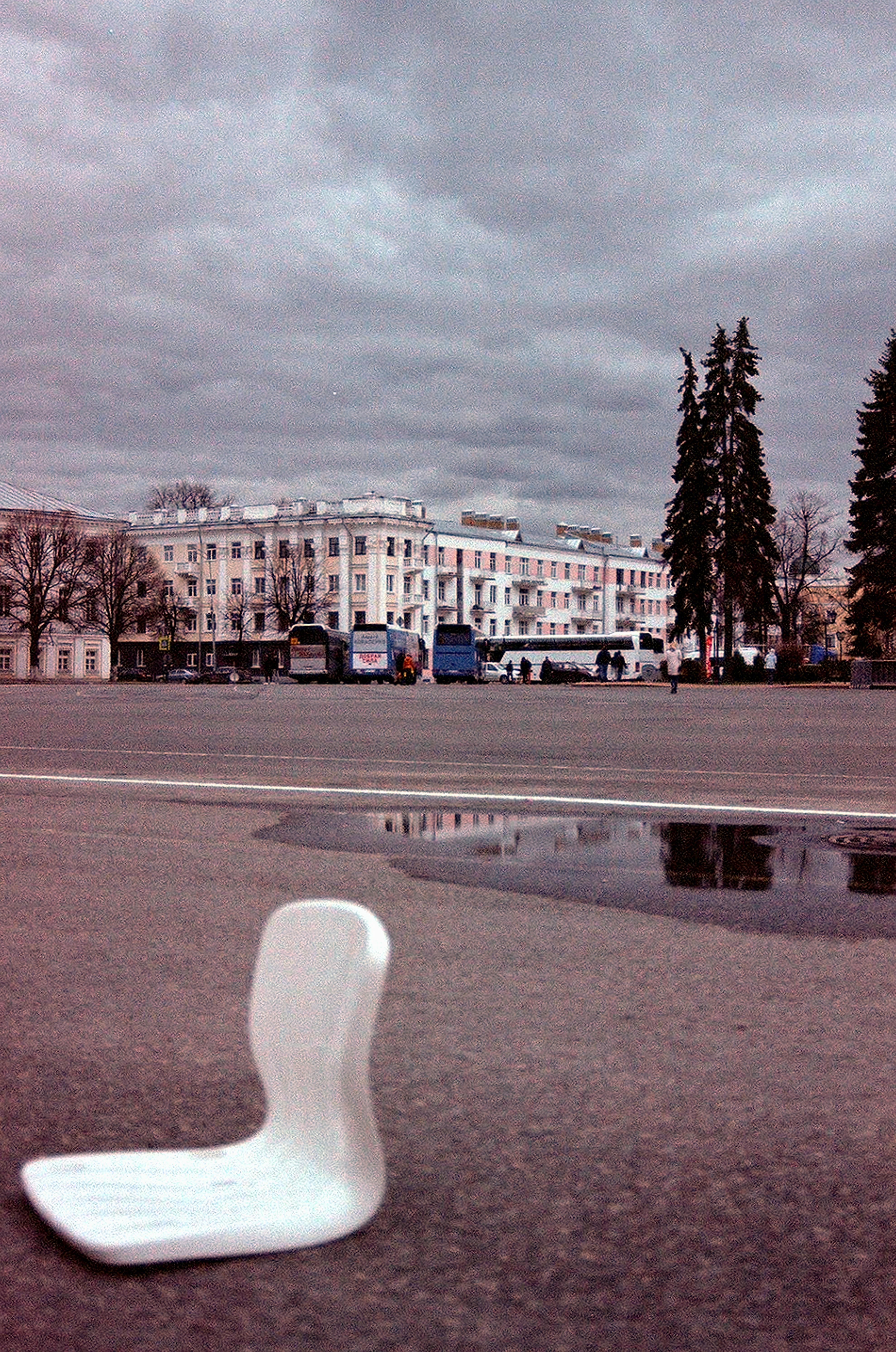 Free Dramatic cloudy urban scene featuring buses and architecture reflecting in a puddle. Stock Photo