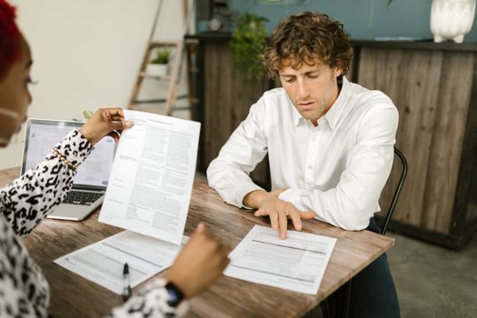 Man in White Long Sleeve Shirt Holding White Paper while Sitting on Black Chair