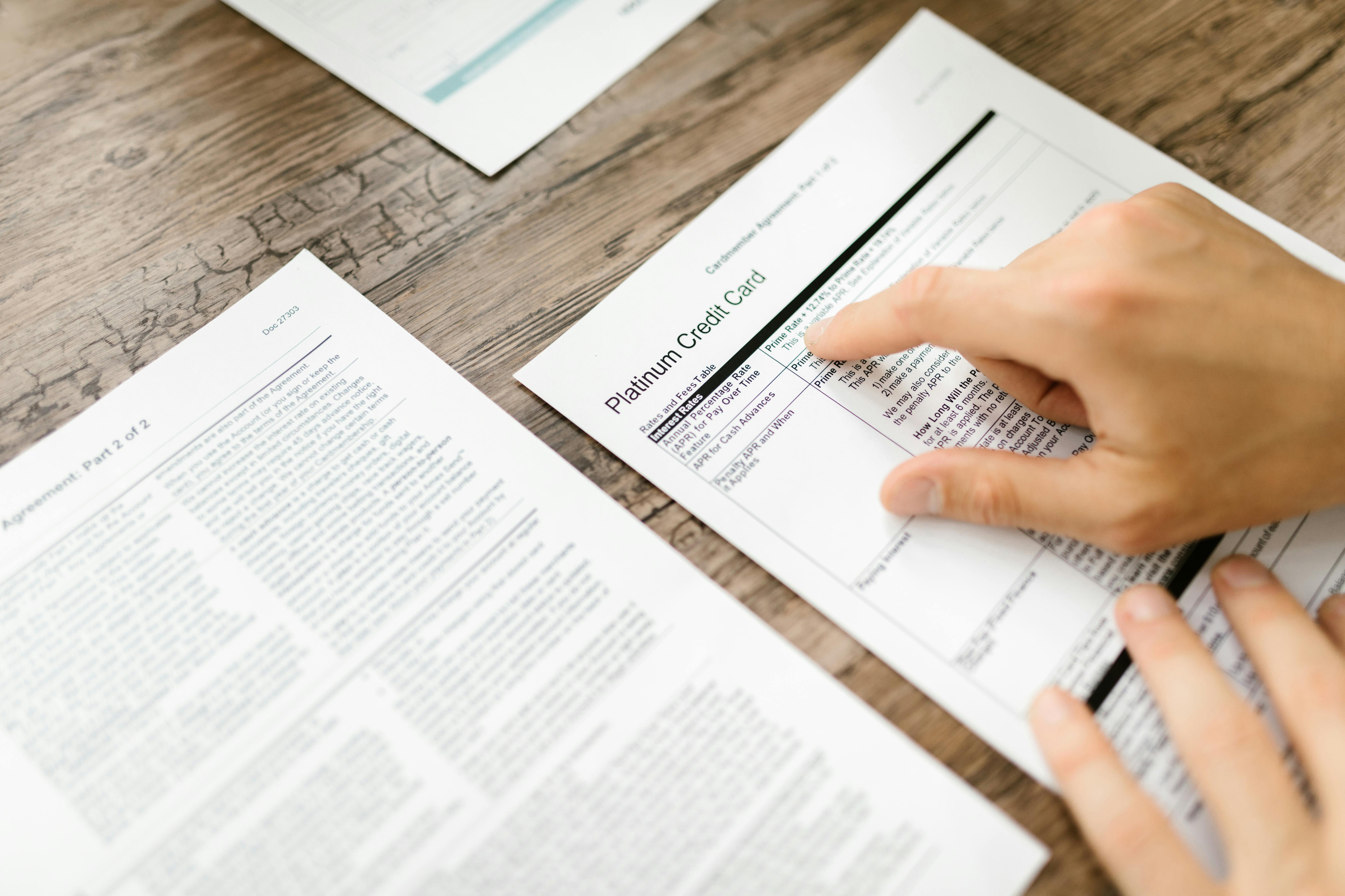 person holding white printer paper on wooden surface