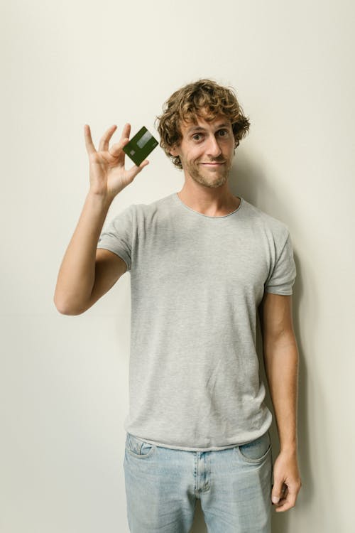 Free Man in Gray Crew Neck T-shirt Holding a Credit Card Stock Photo