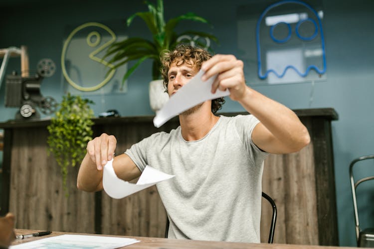 Man In Gray Shirt Tearing White Paper