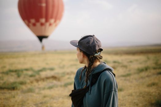 Anonymous woman and air balloon in field