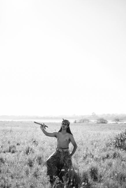 Black and white image of a man holding a spear in a grassy field.