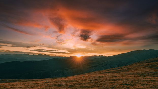 Majestic sunrise over mountain landscape with vibrant sky hues and dramatic scenery.