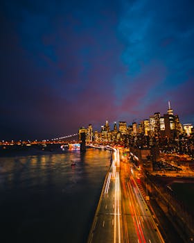 A breathtaking view of New York City's skyline at night with mesmerizing light trails across the river.