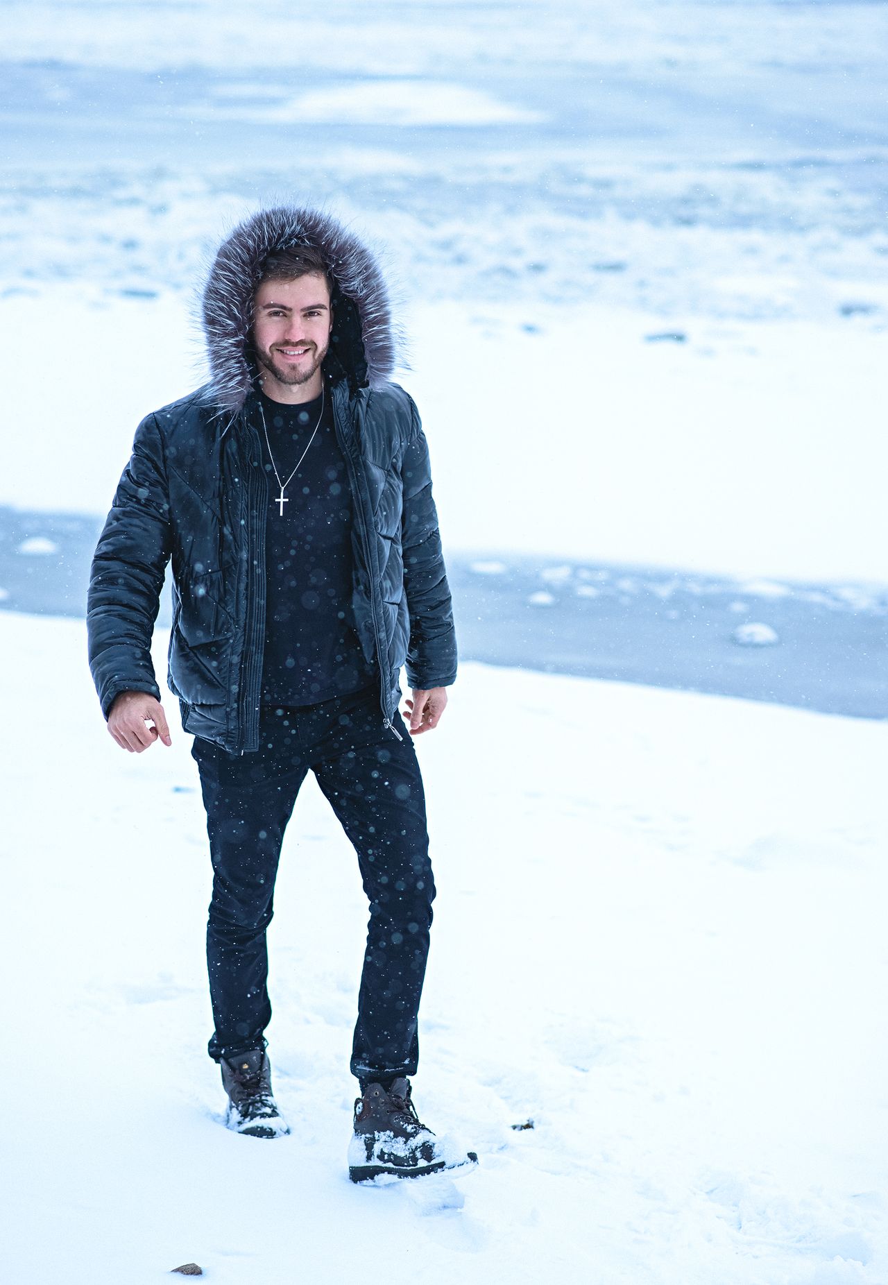 Man in a fur-hood parka standing in falling snow