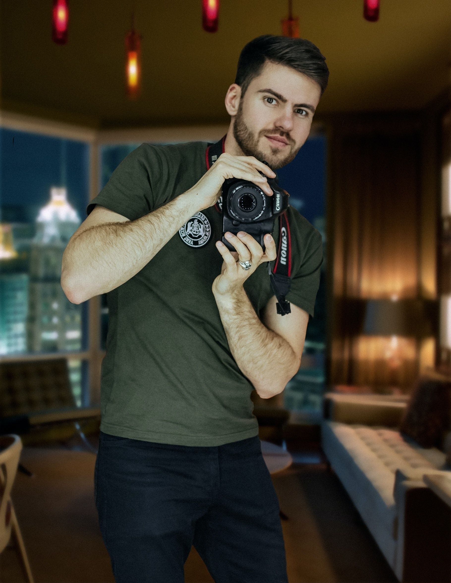 A man holding a camera in a stylish modern indoor setting at night.