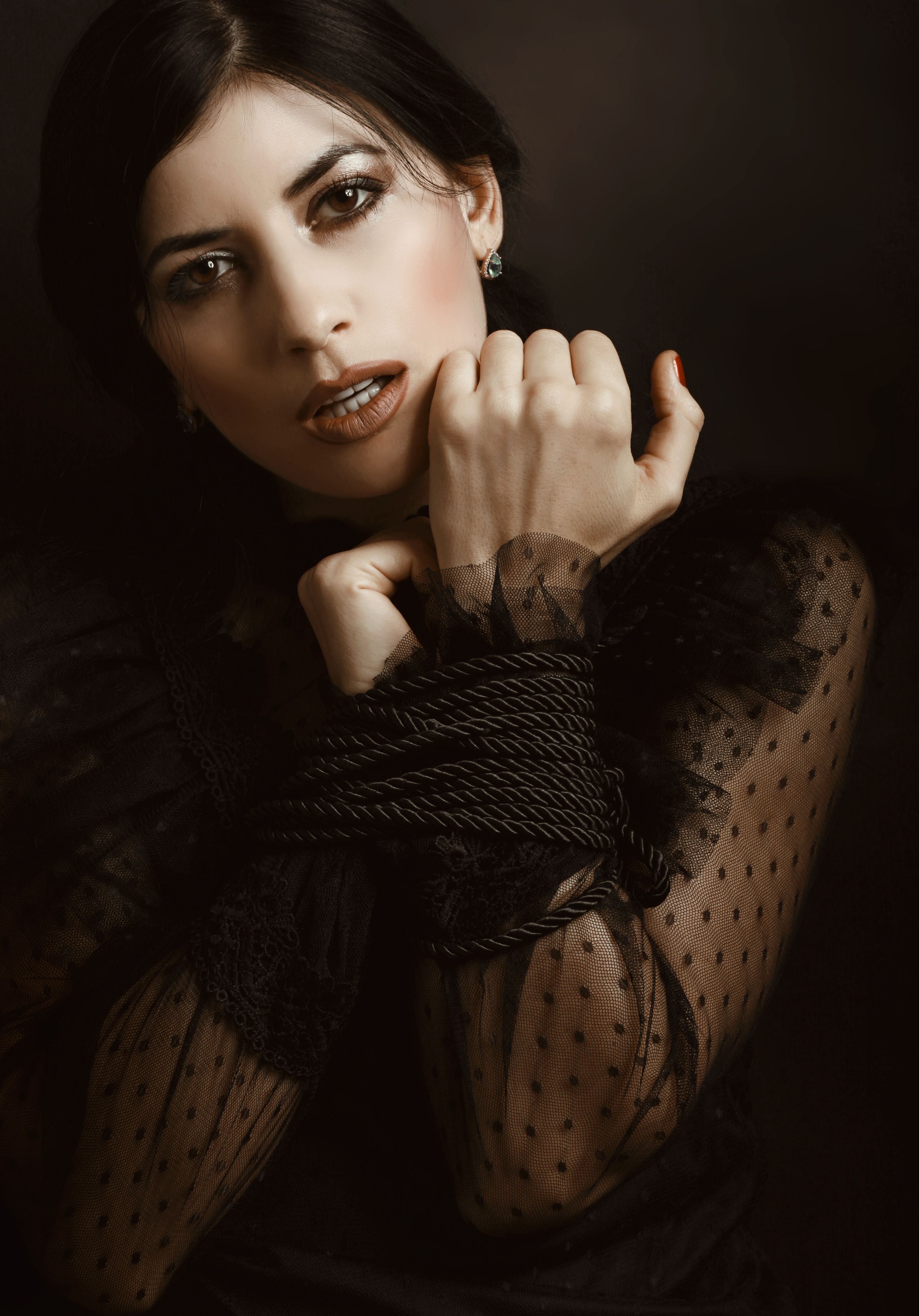 Artistic portrait of a woman with tied hands in an elegant dress, highlighting emotion and expression.