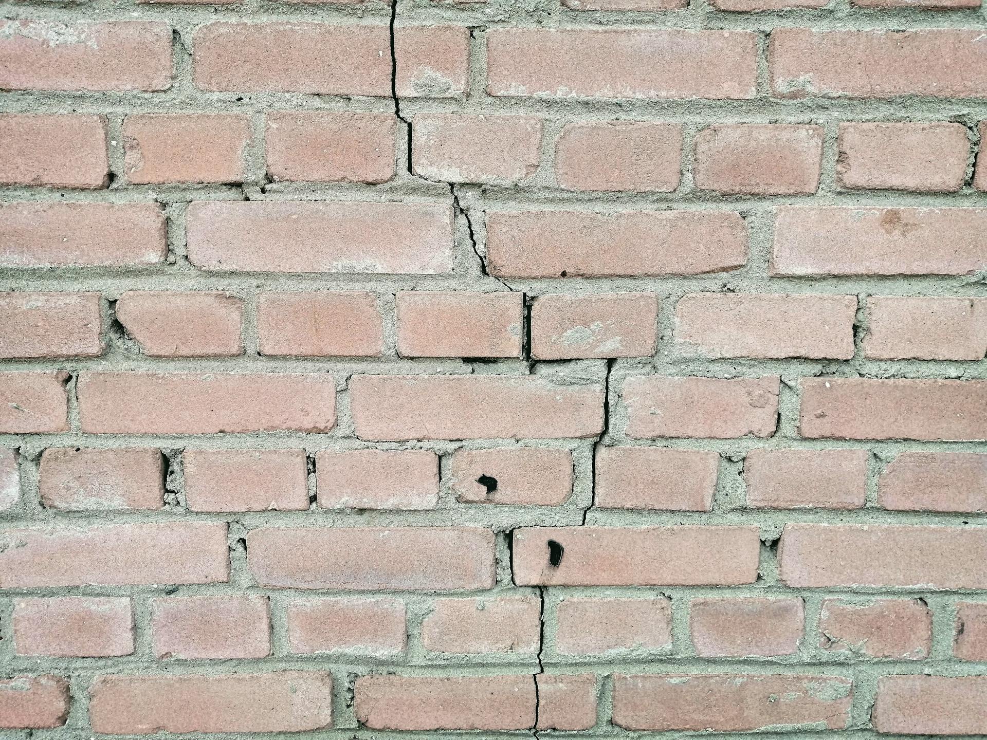 A weathered brick wall with visible cracks and rough cement texture.