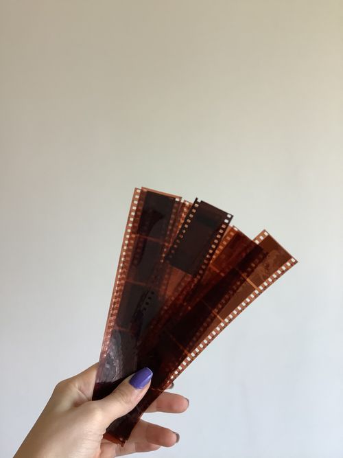Free A hand with manicured nails holds film negatives, showcasing a vintage photographic theme. Stock Photo