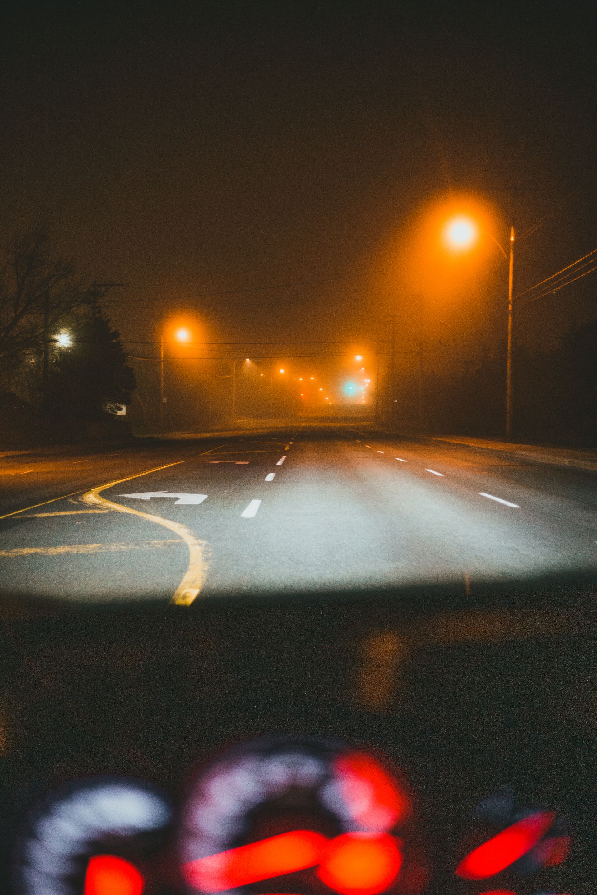 A dark highway at night illuminated by streetlights