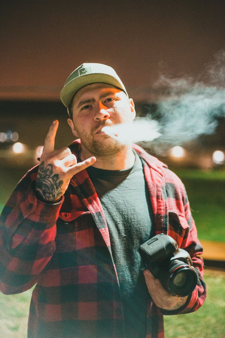 A Photographer Doing The Sign Of The Horns While Smoking