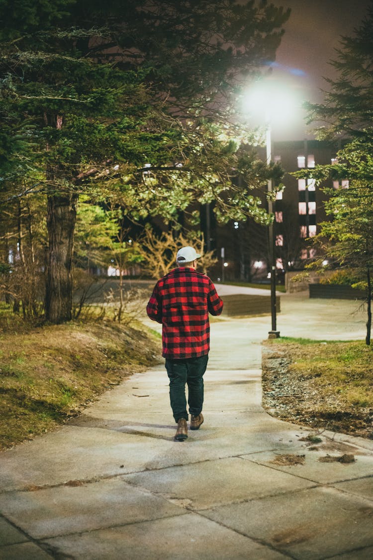 A Man Walking In A Park At Night