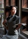 A Woman Holding a Book while Modeling in Traditional Clothing