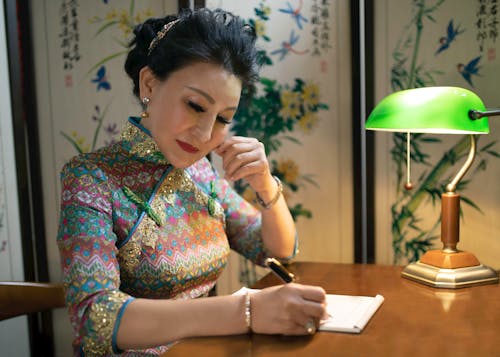  A Woman in a Cheongsam Writing on a Table