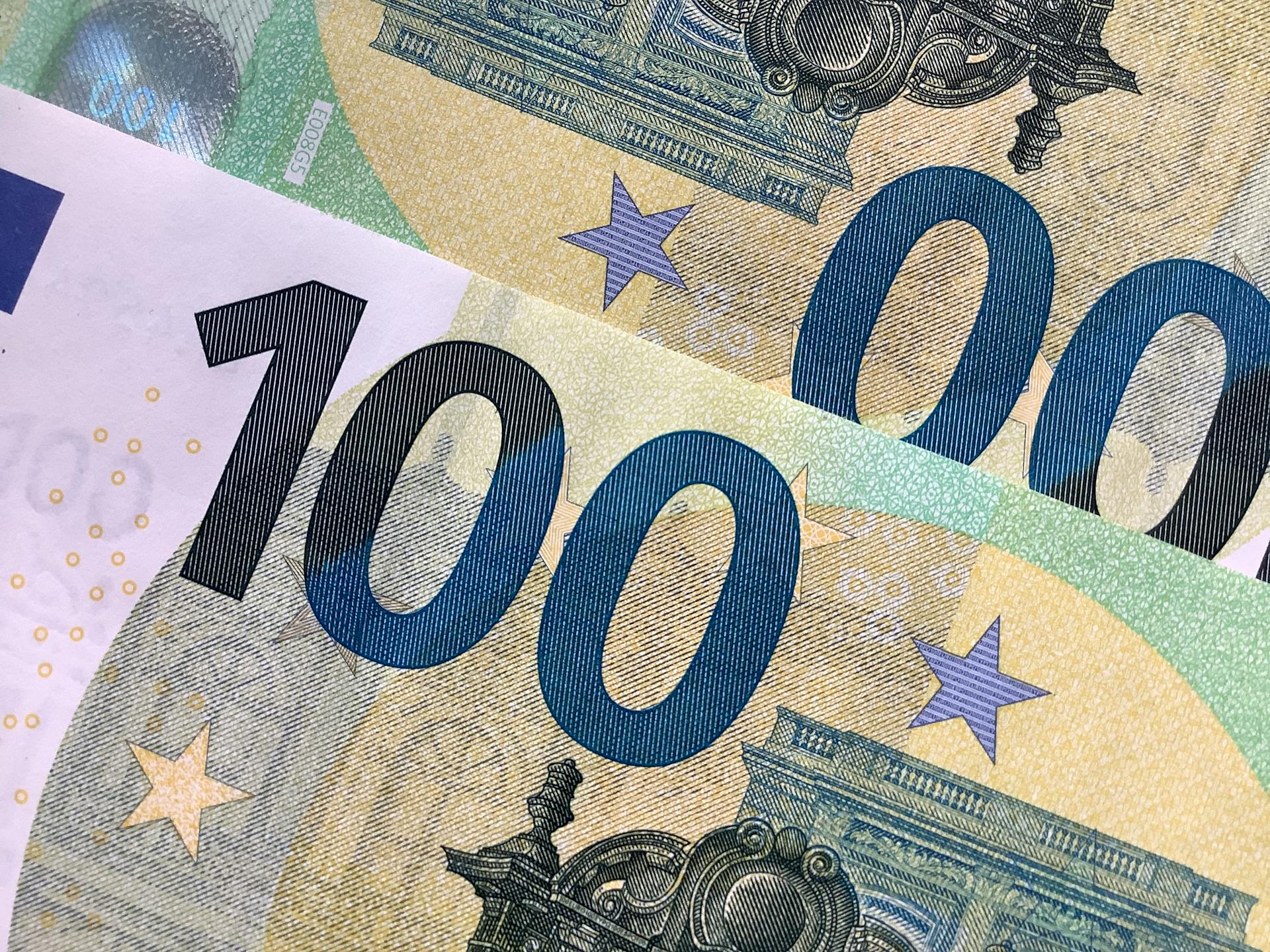 Detailed view of overlapping 100 Euro banknotes showcasing intricate design details.