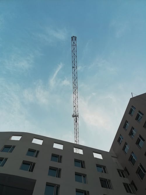 Free A Crane On Top Of A Building Under Blue Sky Stock Photo