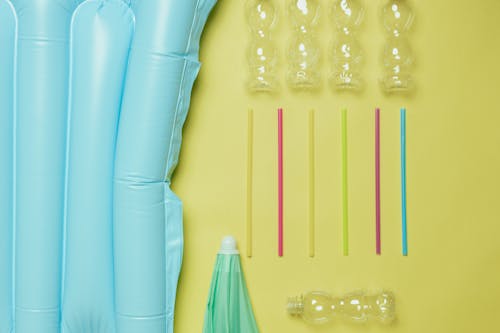 Free Inflatable and Plastic Straw and Bottles on Yellow Surface Stock Photo