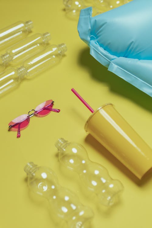 Plastic Containers and Pink Sunglasses on Yellow Surface