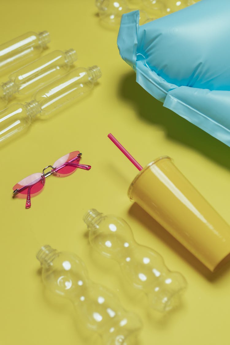 Plastic Containers And Pink Sunglasses On Yellow Surface