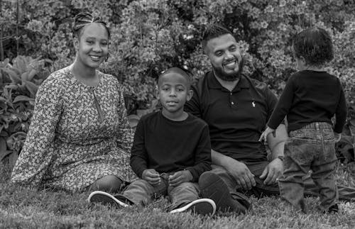 Grayscale Photo of a Family Sitting on Grass
