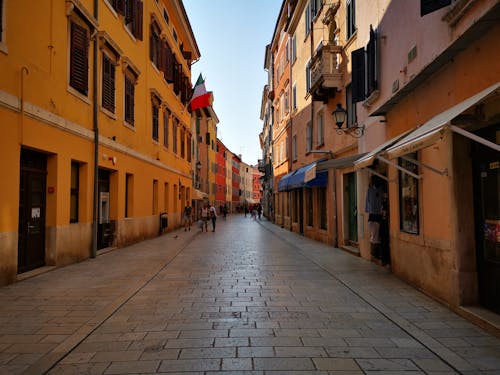 People Walking on the Pathway Between Colorful Houses