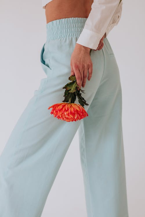 Faceless female with flower in hand on white background