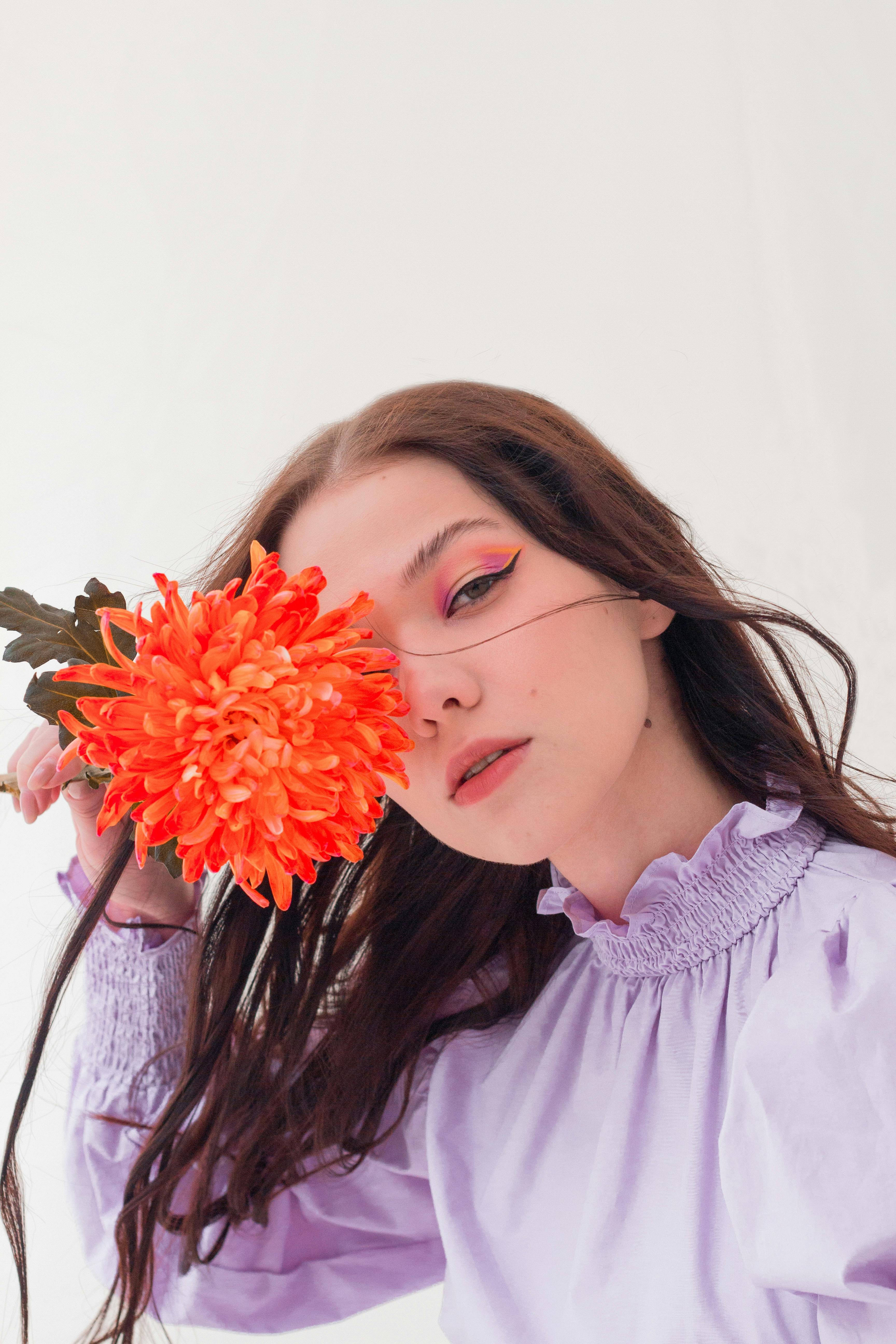 thoughtful woman with flower in studio