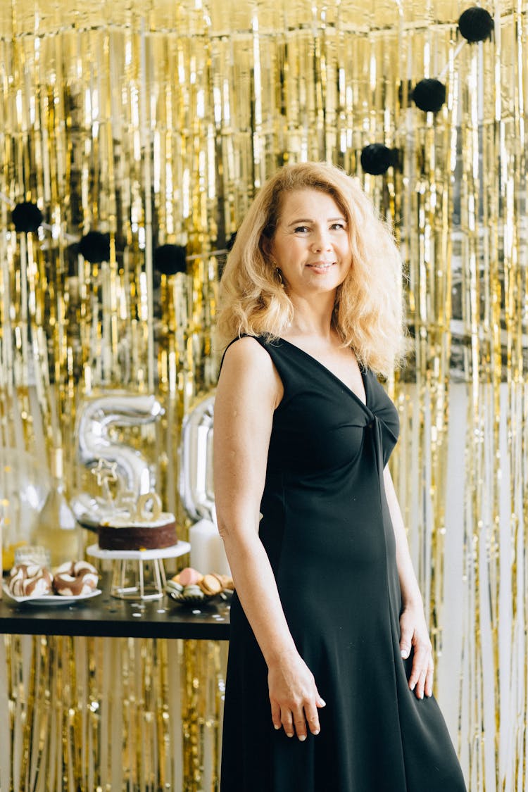 Woman In Black Tank Dress Standing Beside Gold Fringe Curtain