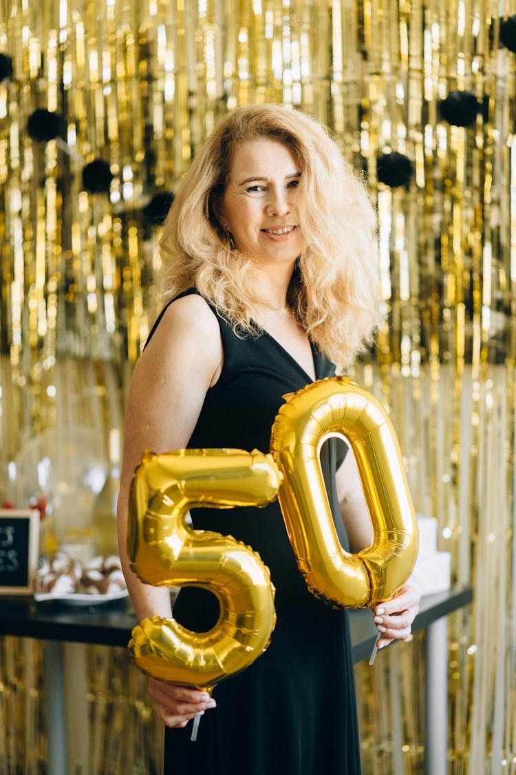 Woman In Black Dress Holding Gold Shaped Balloons