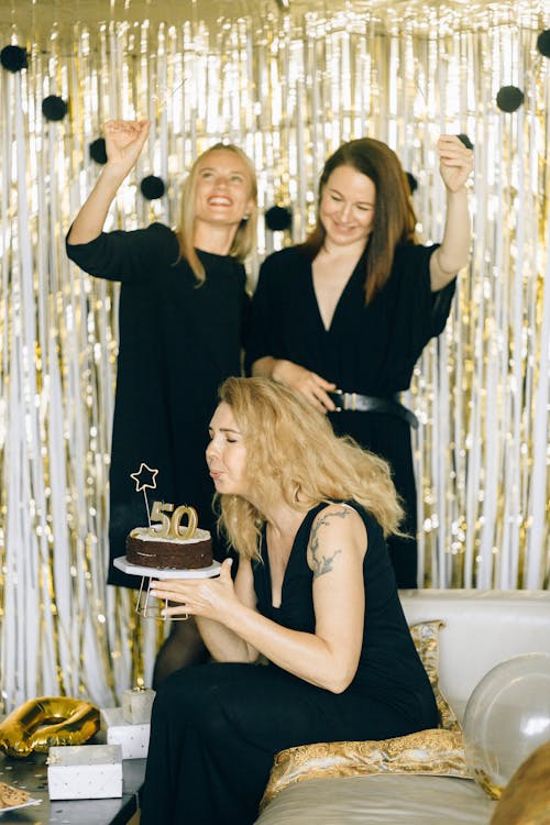 Woman Sitting on Couch Blowing Birthday Cake