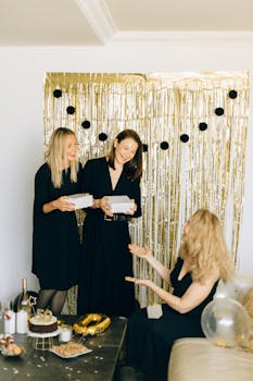 Three women sharing gifts at a stylish indoor birthday celebration.