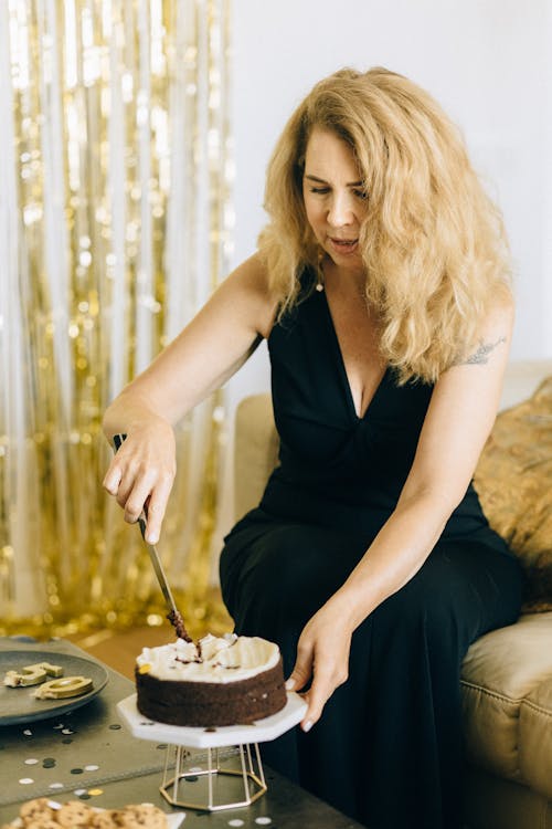 Woman in Black Dress Holding Silver Knife Slicing Her Cake