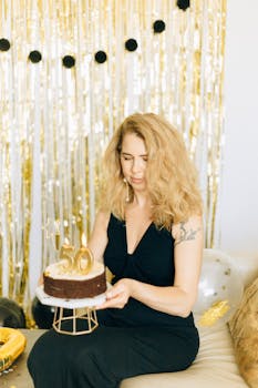 Elegant woman celebrating her 50th birthday with a cake indoors.