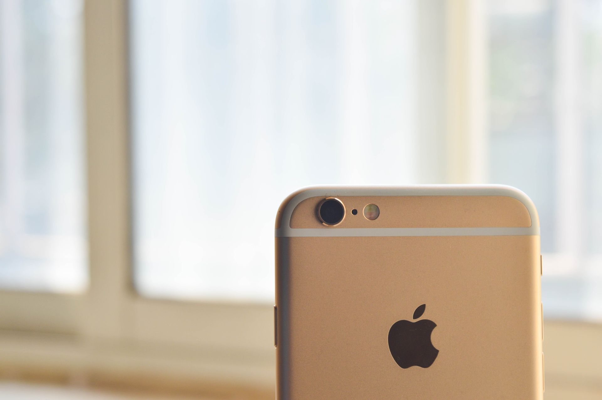 A close-up shot of a smartphone focused on the camera in front of a sunny window.