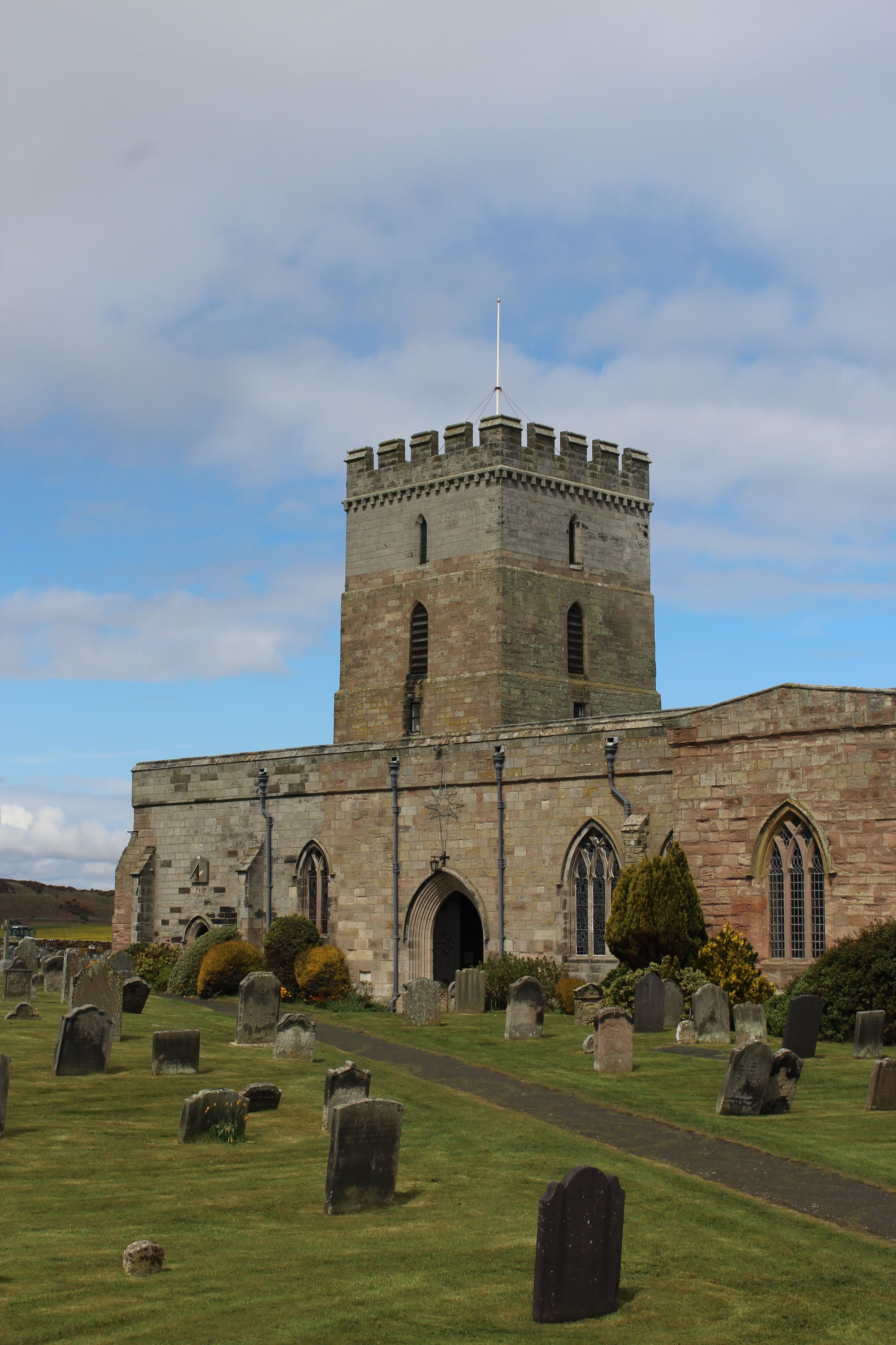 Historic St Aidan's Church amid a serene graveyard in Bamburgh, England.