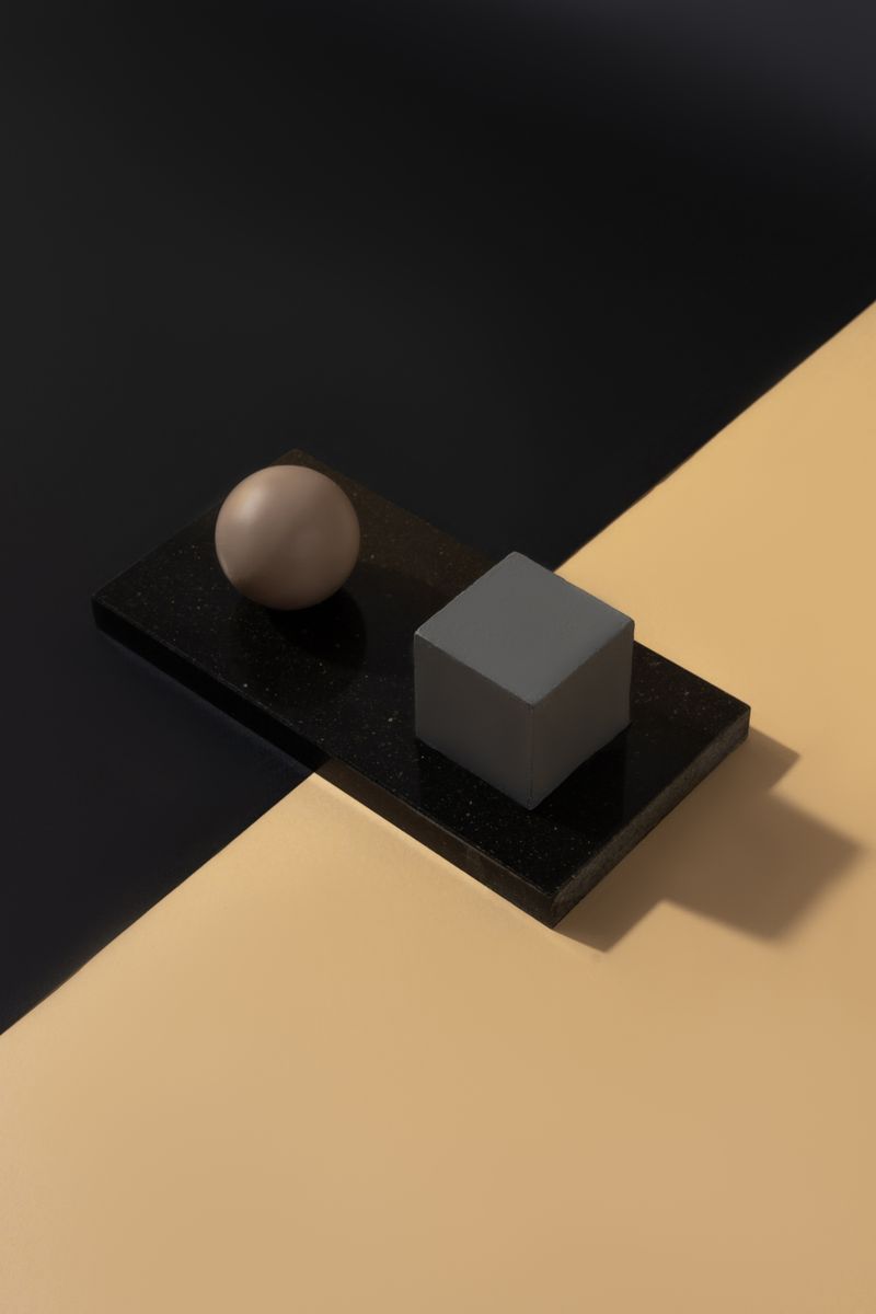 Minimalistic composition featuring geometric shapes on black and beige split background.