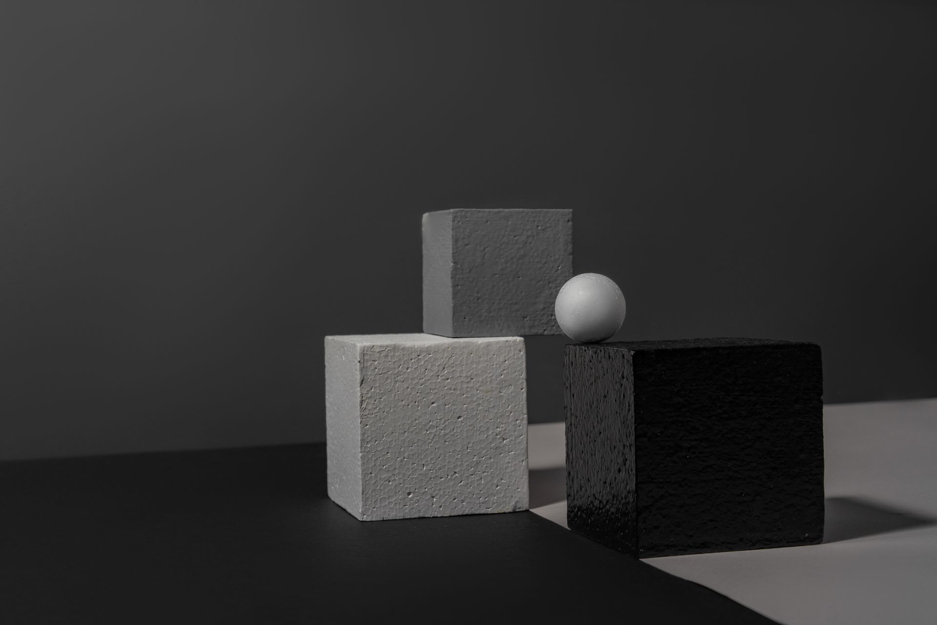 Abstract still life featuring gray geometric shapes in a studio setting.