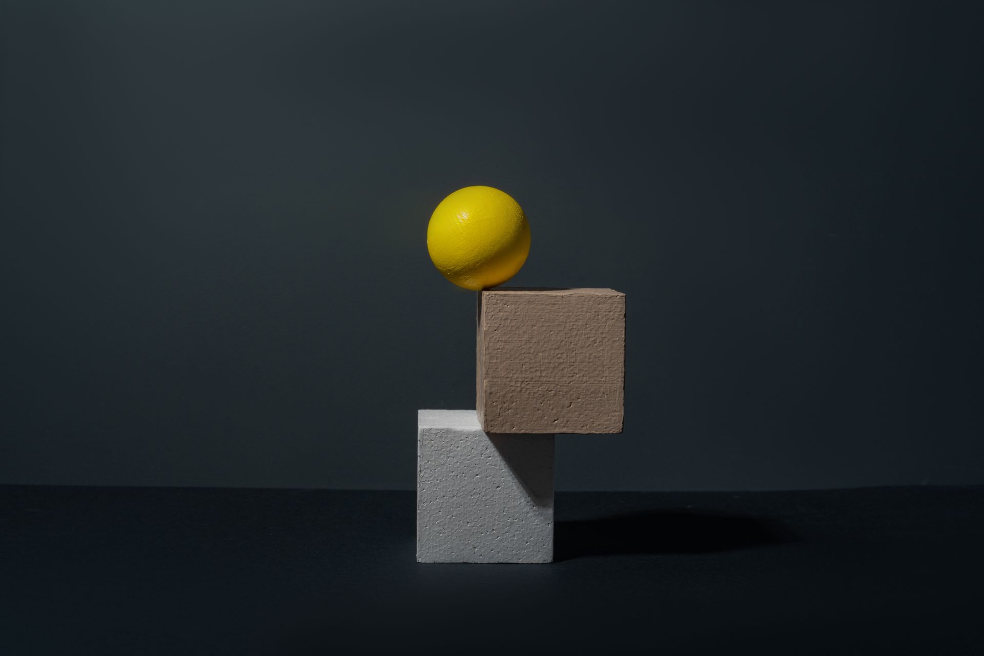Creative composition featuring a yellow sphere and blocks in a minimalist still life setup.