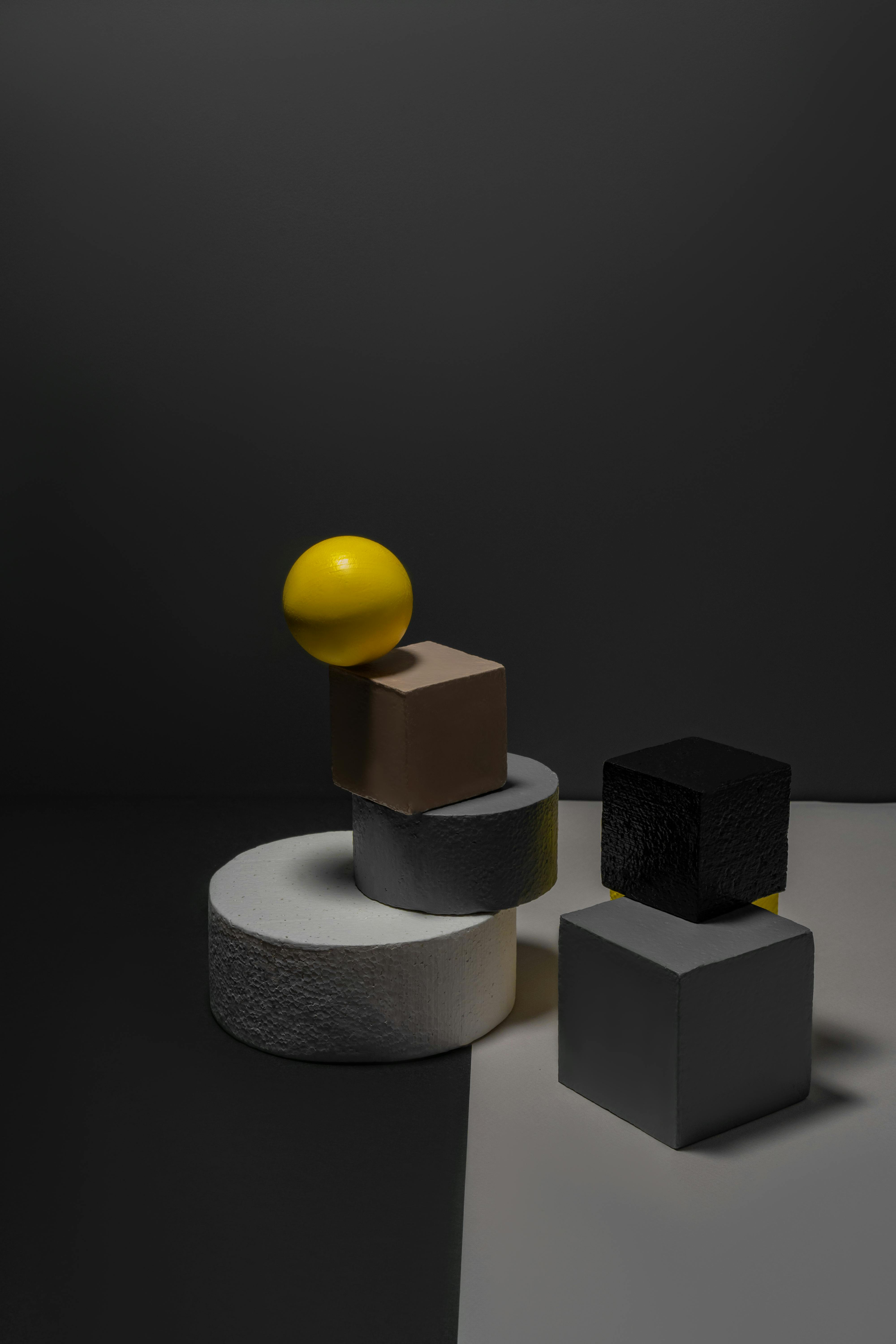 yellow ball on a cube s edge and geometrical shapes