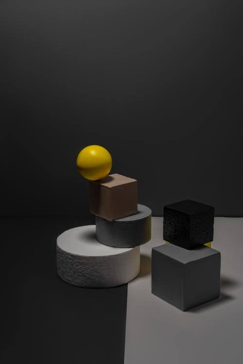Free Yellow Ball on a Cube's Edge and Geometrical Shapes Stock Photo