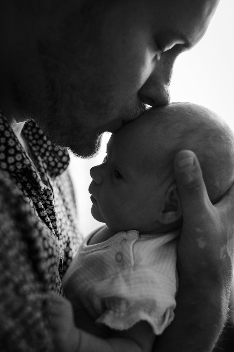 Father Kissing Cute Newborn Baby