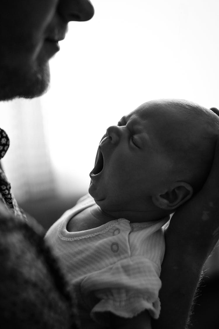 Crop Father With Yawning Baby At Home