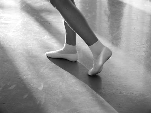 Crop dancer in ballet slippers on floor