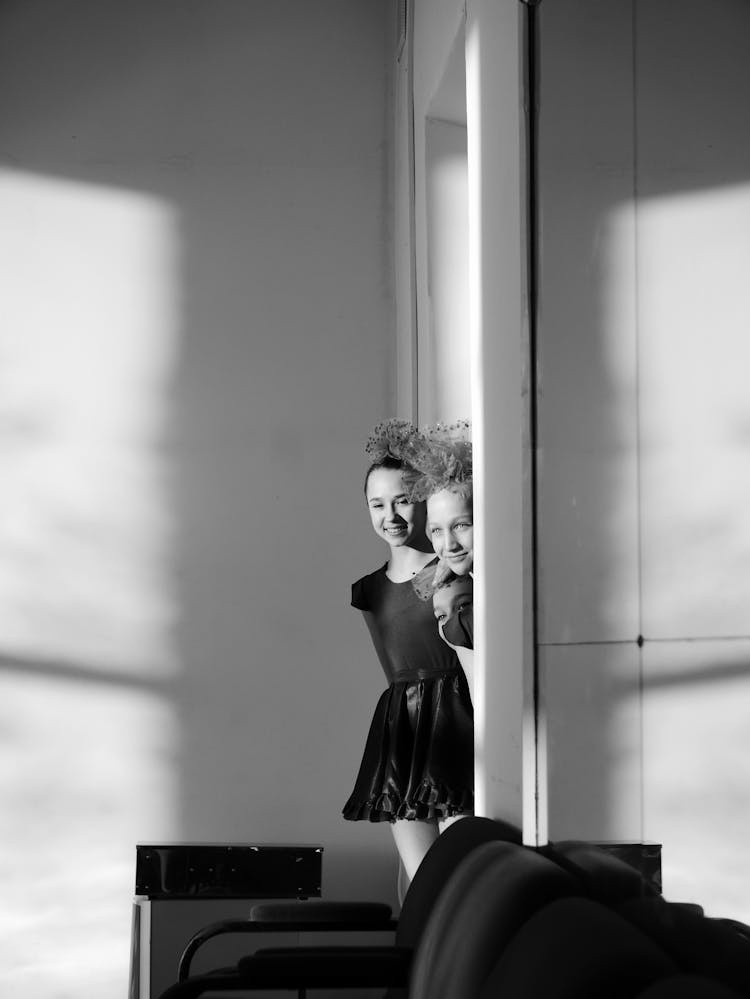 Smiling Ballerinas Peeping Out Of Door In Dancing Hall