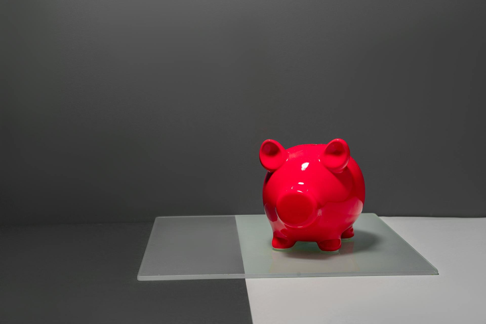 A vibrant red piggy bank against a minimalist and contrasting studio background, ideal for finance themes.