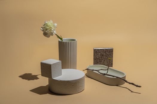 Modern still life featuring a flower in a vase with geometric shapes on a neutral background.