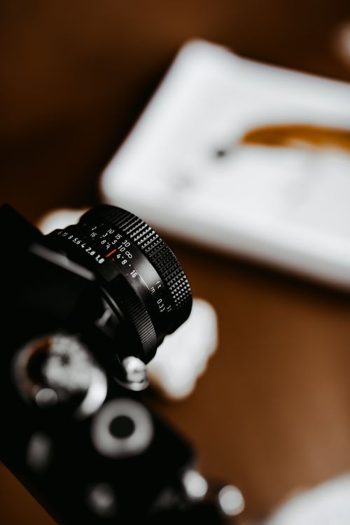 Free A detailed view of a camera lens on a table with a blurred background, focusing on photography equipment. Stock Photo