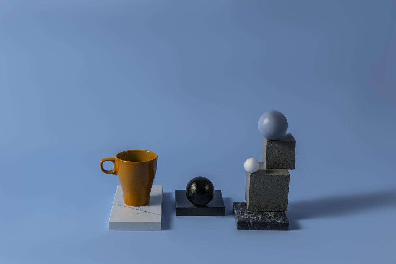 modern minimalist composition with spheres and a cup on blue backgroun